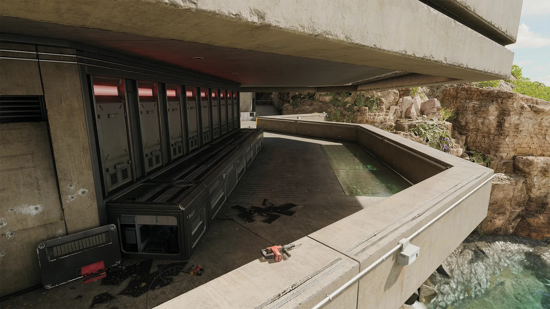 A modern concrete balcony overhangs a rocky cliffside above ocean water, featuring exposed machinery, red accent lighting, and industrial storage lockers lined against the wall.