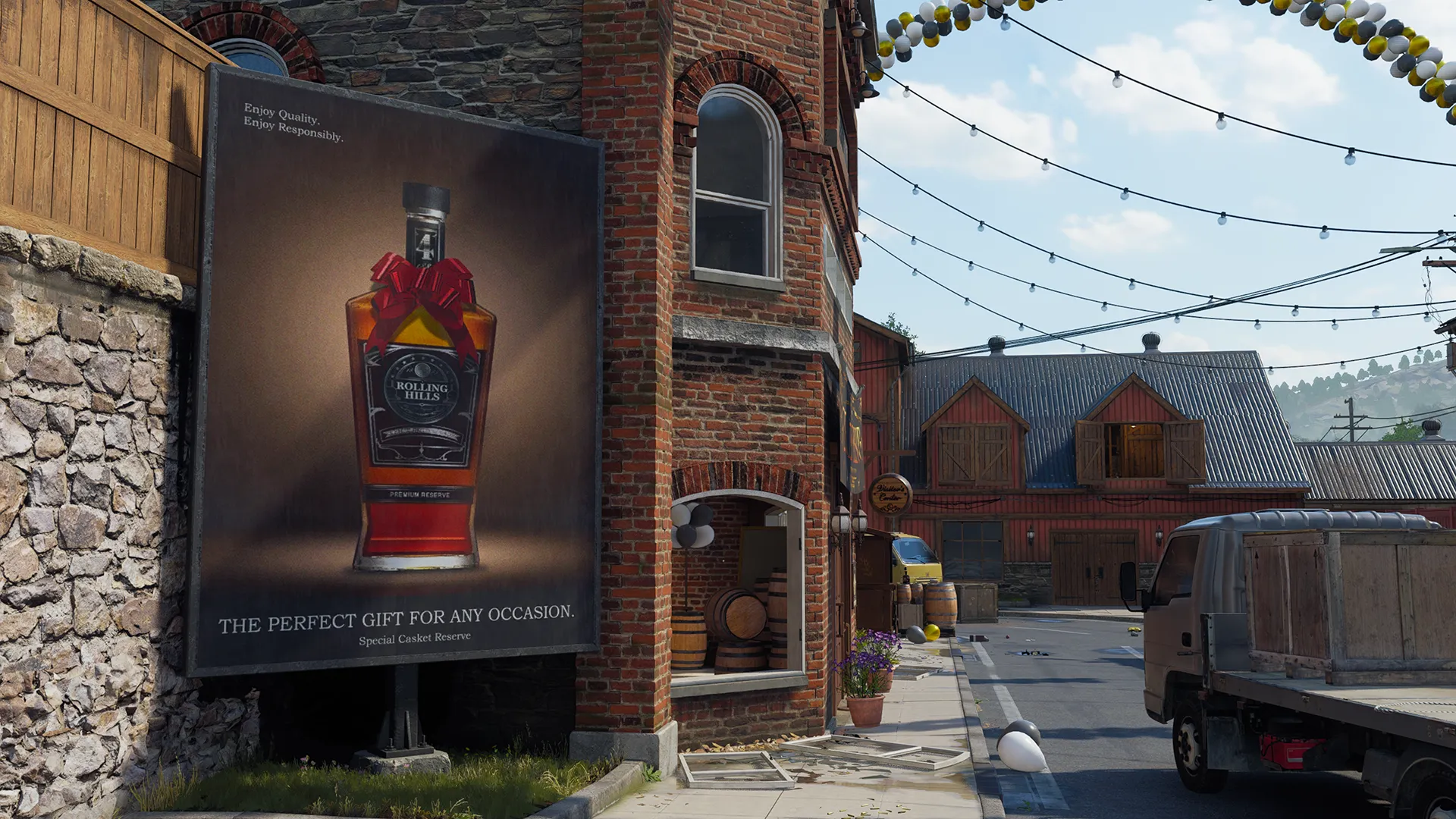 A brick building lines the street beside a large billboard advertising a bottle of “Rolling Hills” whiskey as string lights and balloons hang above the road. Parked delivery trucks, barrels, and scattered debris create a festive but slightly disordered village scene.