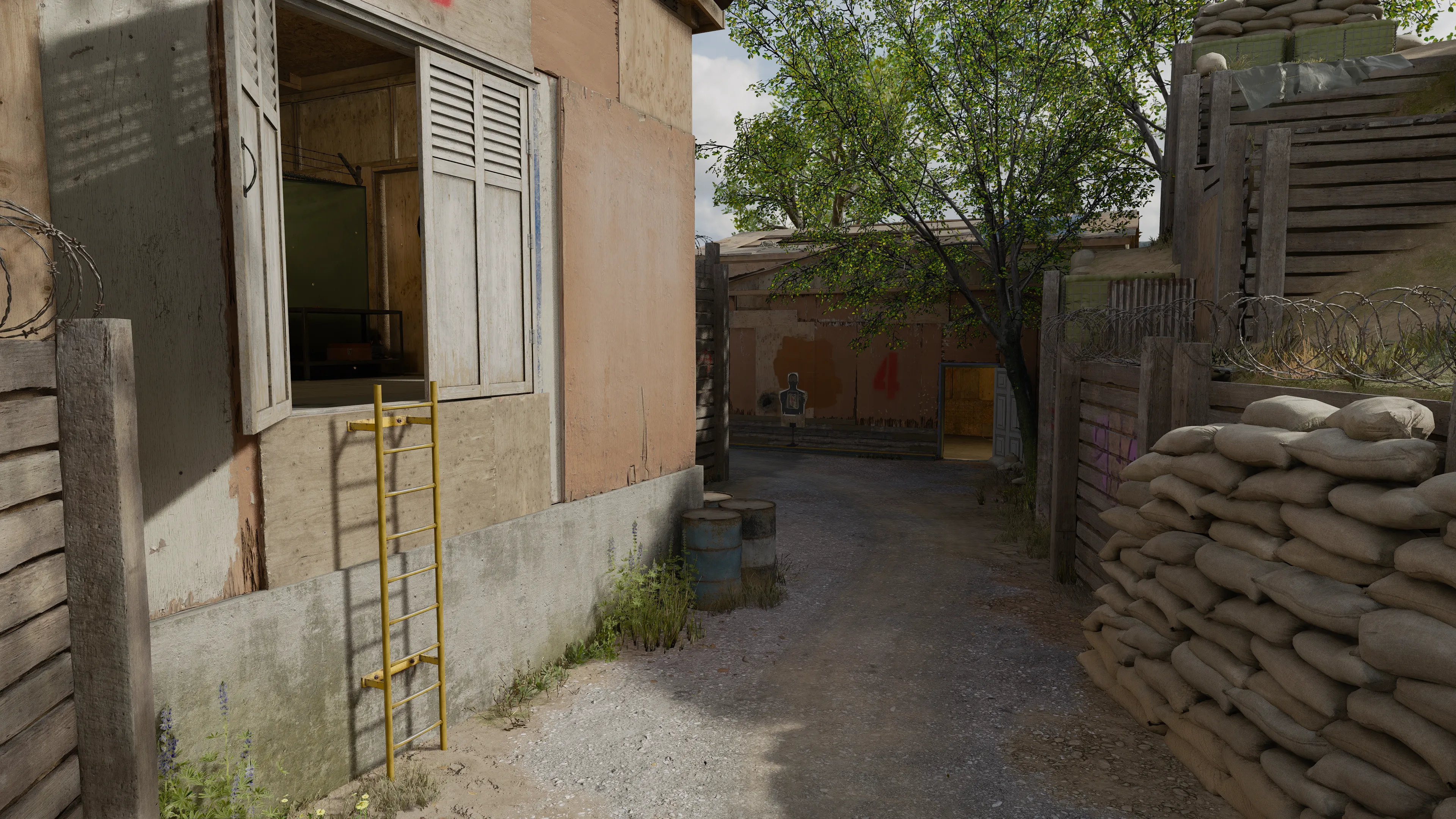 A narrow dirt path beside a building with a yellow ladder and sandbag barriers, leading toward a shooting range target area.