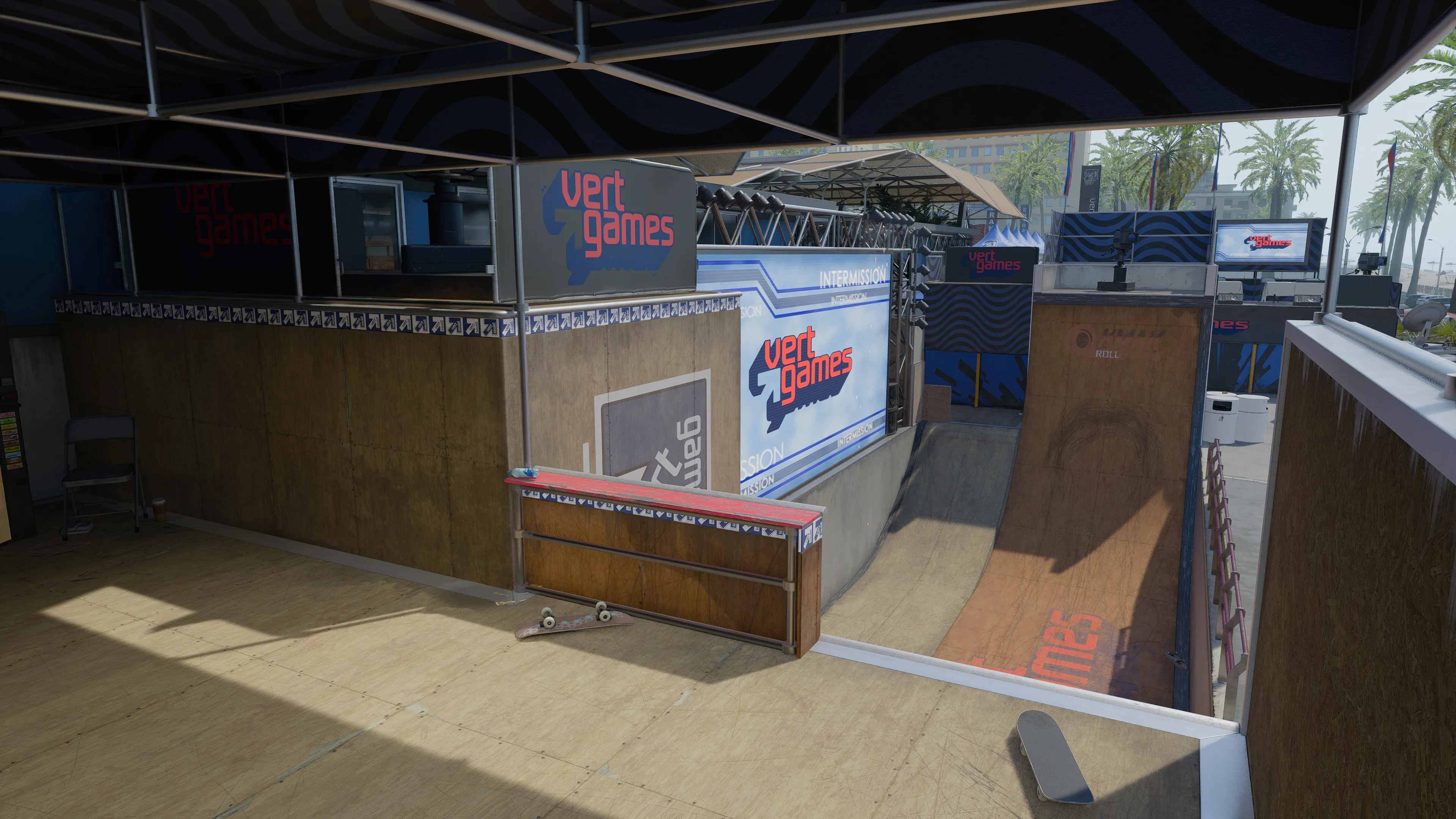 A covered skate ramp area with Vert Games banners and an event screen displaying “Intermission” above the ramp.