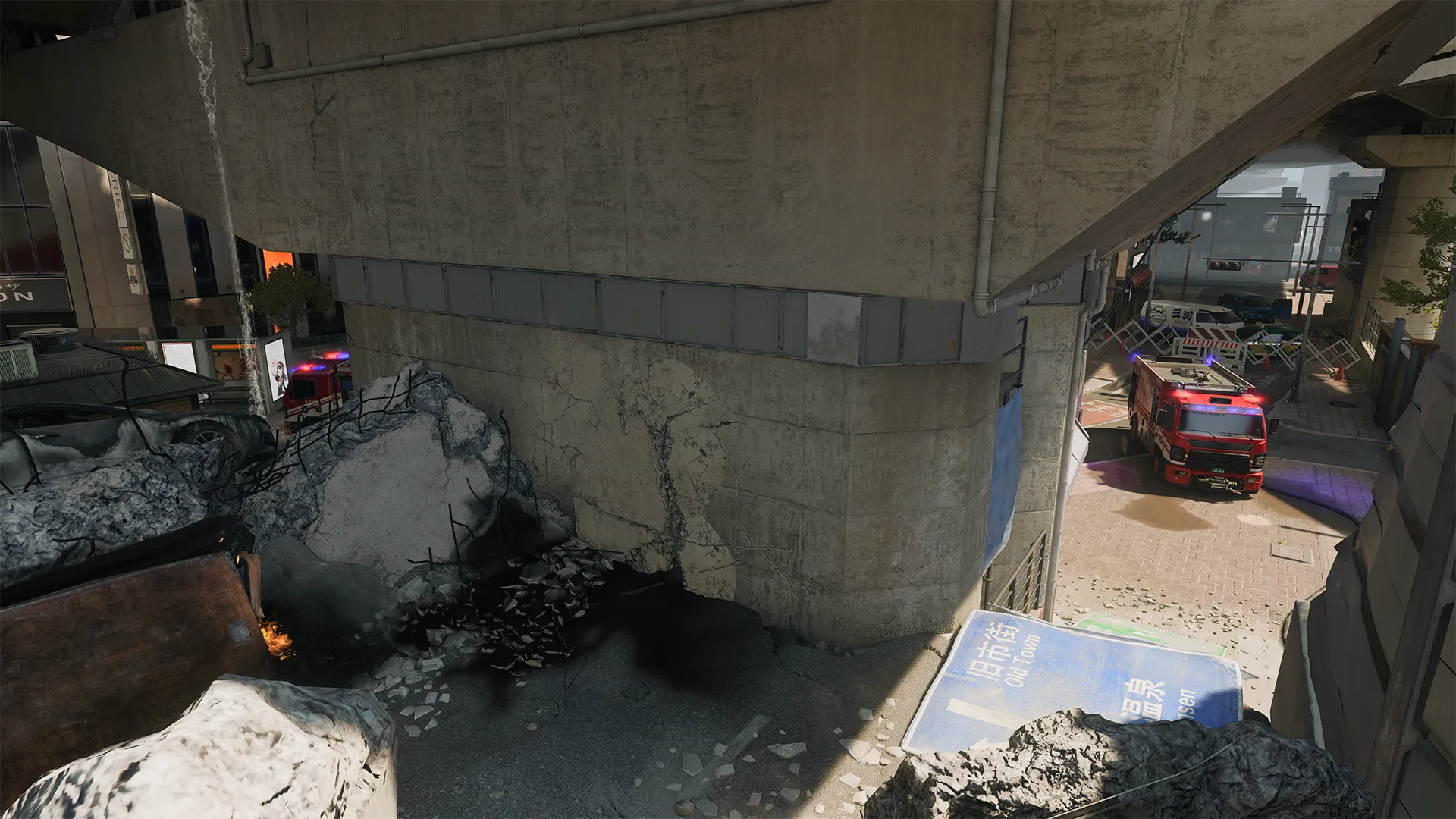 Collapsed overpass with fire trucks and barricades below, debris scattered across a damaged roadway.