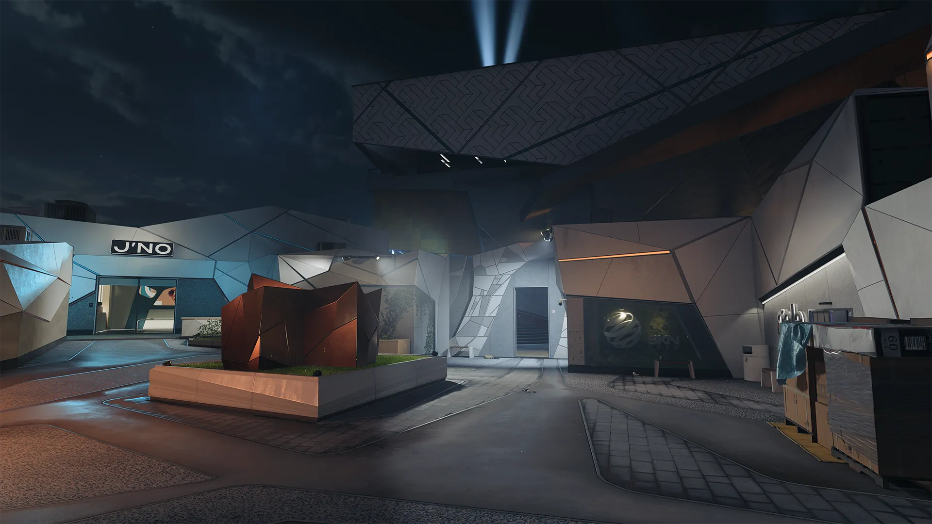 Futuristic plaza at night with angular buildings, “J’NO” sign, and a red sculpture in a lit courtyard.