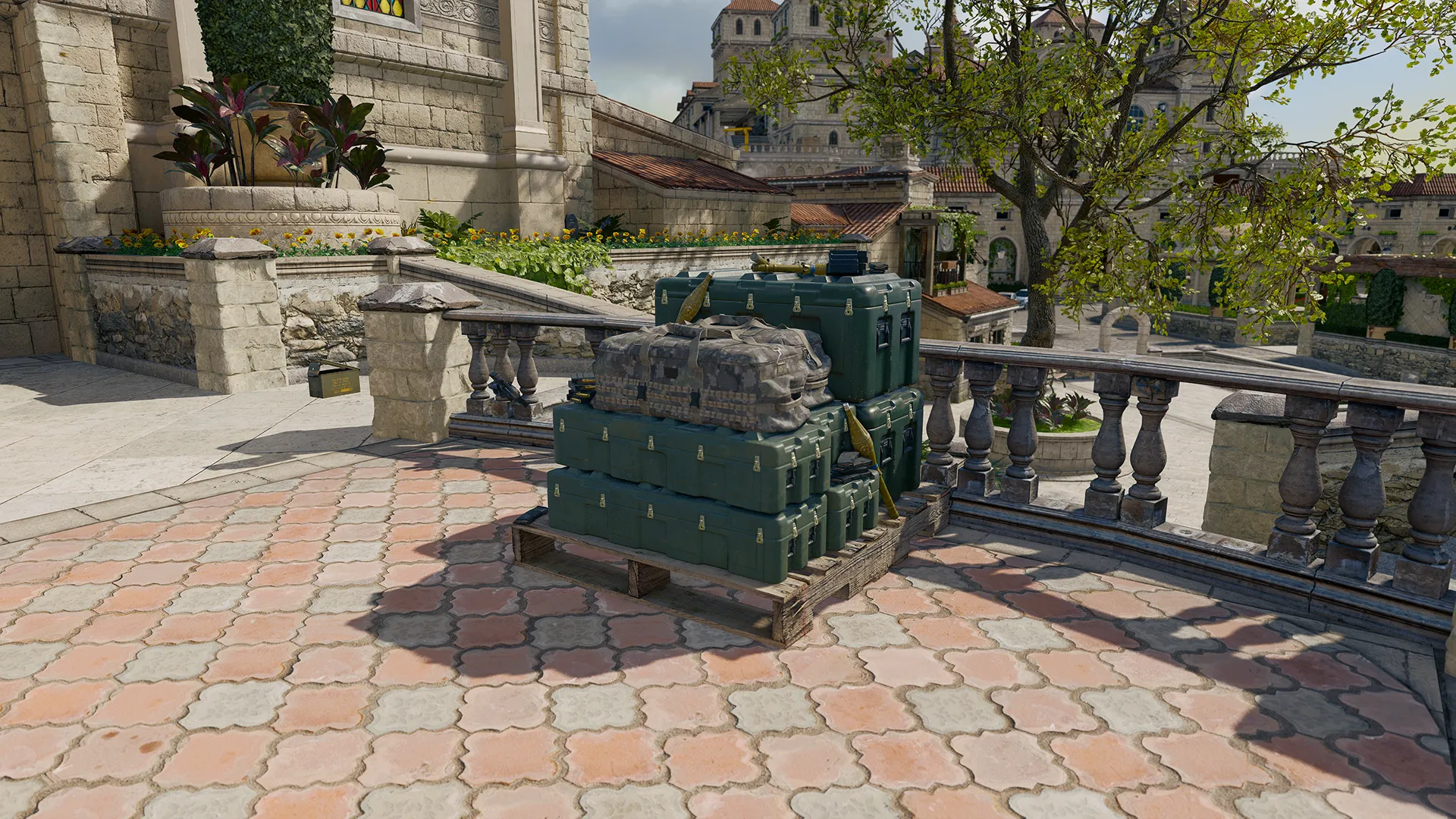 Stack of green ammo crates beside a stone terrace overlooking a coastal town.